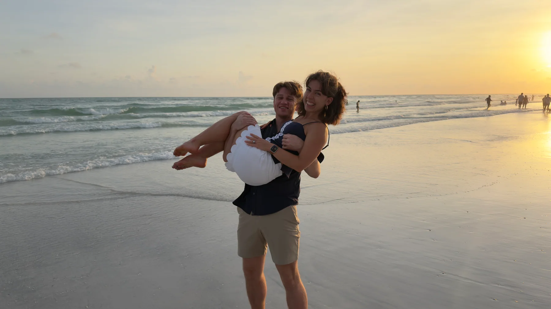 Hugh carrying Anna Margaret on a beach at sunset