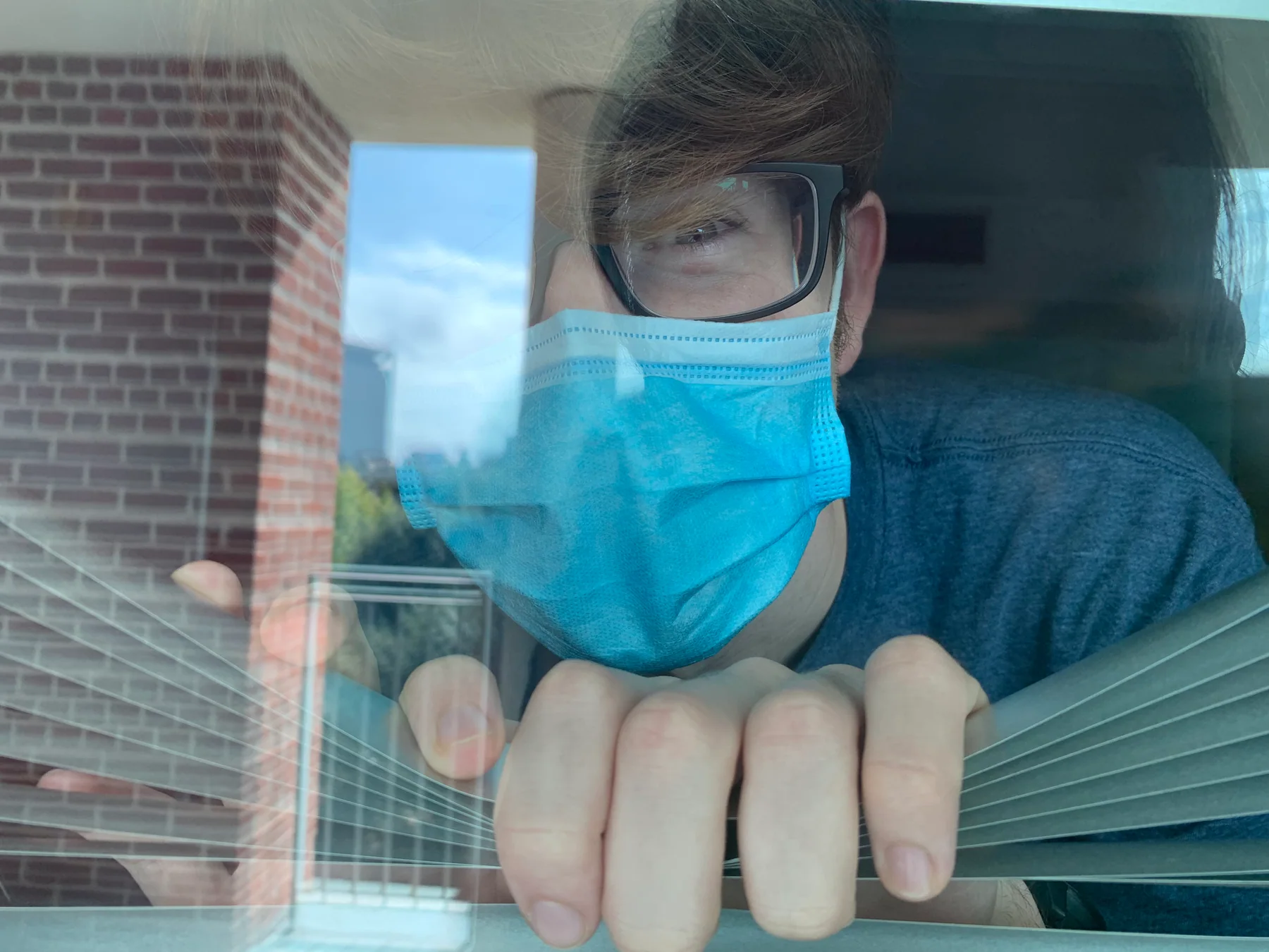 Hugh looking through a window while wearing a mask in 2020